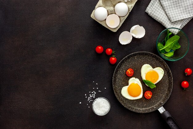 Cucinare uova fritte a forma di cuore in padella con pomodori e verdure