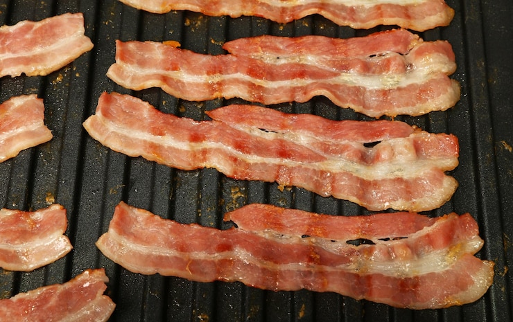 Foto cucino da vicino fette di pancetta sulla griglia elettrica