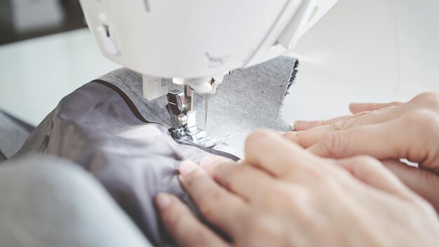 Cucire panno grigio su una macchina da cucire bianca mani femminili