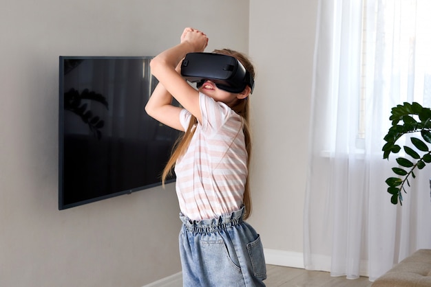 Cuffia avricolare d'uso degli occhiali di realtà virtuale dell'adolescente e giocare, scatola del vr. tecnologia, nuova generazione, concetto di progresso. Ragazza che prova a toccare gli oggetti nella realtà virtuale.