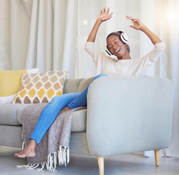 Cuffie donna nera e felice sul divano per ballare e ascoltare musica in soggiorno con sorriso Auricolare Ragazza afroamericana e femmina in streaming audio radio e sul divano per la felicità