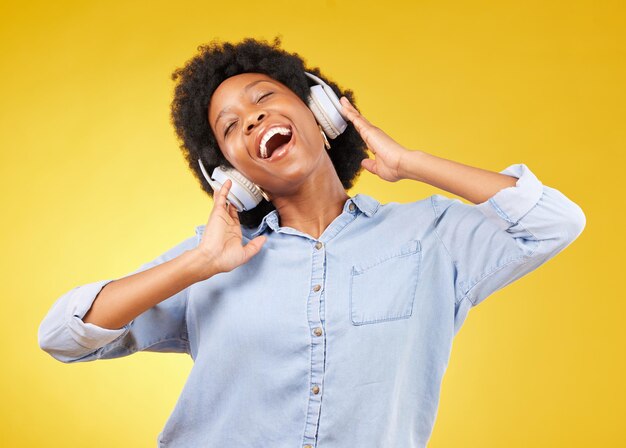 Cuffie donna nera e libertà di ascoltare musica e felicità con la danza su sfondo giallo studio Felice donna spensierata e cantare insieme alla radio in streaming audio con divertimento e tecnologia