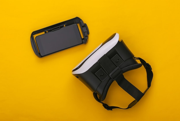 Cuffie e smartphone per realtà virtuale su sfondo giallo. Gadget moderni. Vista dall'alto