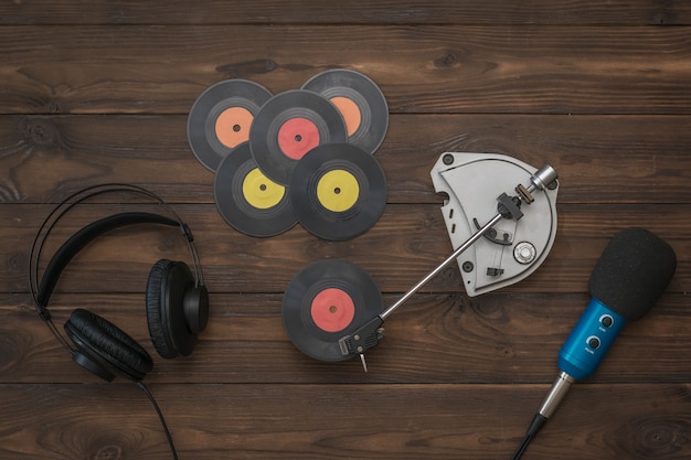 Cuffie, microfono e giradischi vintage con dischi in vinile su un tavolo di legno. Tecnica retrò per la riproduzione di musica.