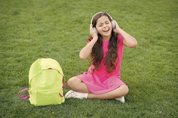 Cuffie per ragazza che ascolta musica Tempo piacevole Cuffie per bambini per ascoltare musica Tecnologia moderna Studentessa gode della melodia Ascolta musica rilassante all'aperto Ragazza del bambino Goditi la musica prato di erba verde