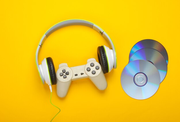 Cuffie stereo con gamepad, dischi cd su superficie gialla