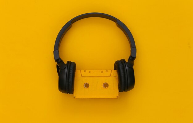 Cuffie stereo nere con una cassetta audio retrò su un giallo