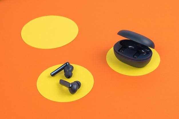 Cuffie wireless e una custodia su uno sfondo astratto giallo arancione Un popolare gadget wireless