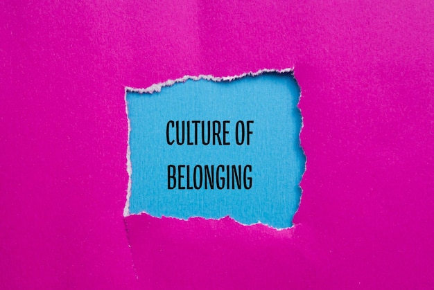 Cultura delle parole di appartenenza scritte su carta rosa strappata con sfondo blu