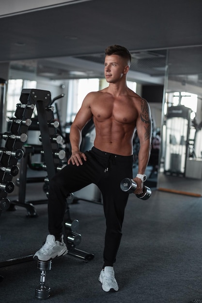 Culturista di fitness maschile muscoloso sportivo con un corpo muscoloso che si allena in palestra