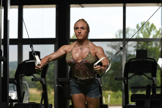 Culturista donna sta lavorando sul petto con cavo crossover in palestra