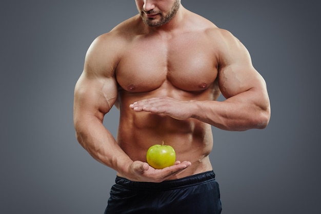 Culturista senza camicia che tiene una mela nelle sue mani