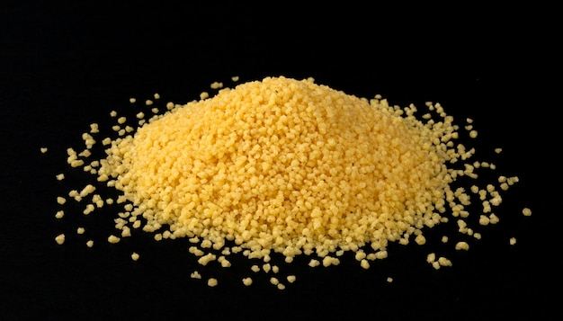 Cumulo di couscous secco semole isolati su sfondo nero, primo piano