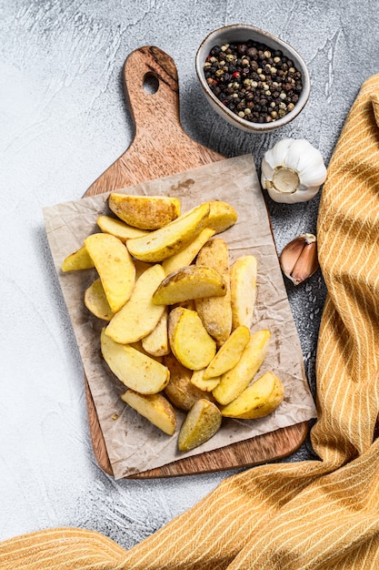 Cunei congelati delle patate fritte su un tagliere di legno.