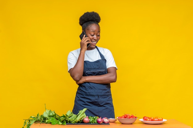 Cuoca africana femminile che fa telefonata, sentendosi felice