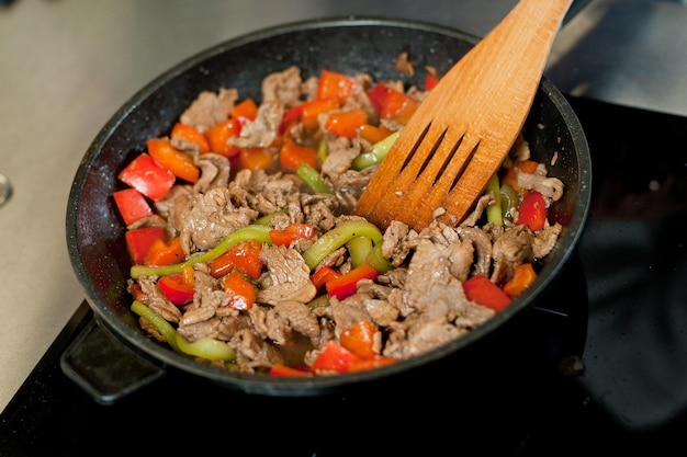 Cuocere la carne in padella con le verdure