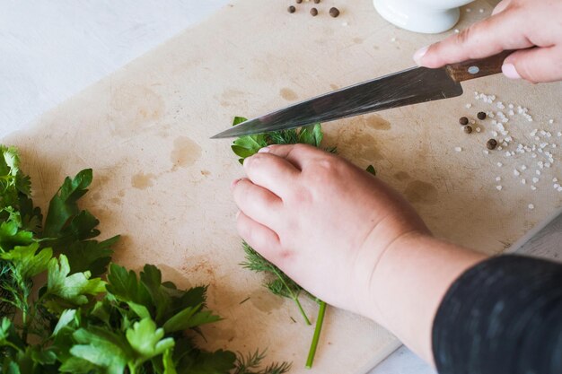 Cuocere la donna che taglia il prezzemolo verde sulla scrivania in legno Processo di cottura cibo biologico sano e decorazione immagine vista dall'alto