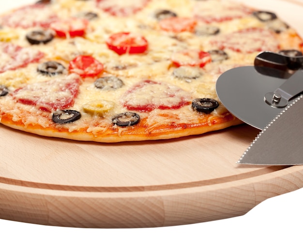 Cuocere la pizza su un tagliere con coltello tondo e spatola. isolato