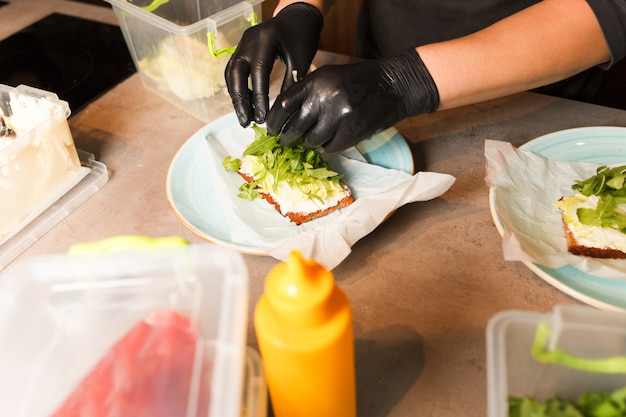 Cuocere le mani preparando e producendo sandwich.