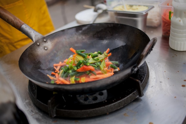 cuocere le verdure fritte in una padella wok sul fuoco Lo chef sta mescolando le verdure nel wok