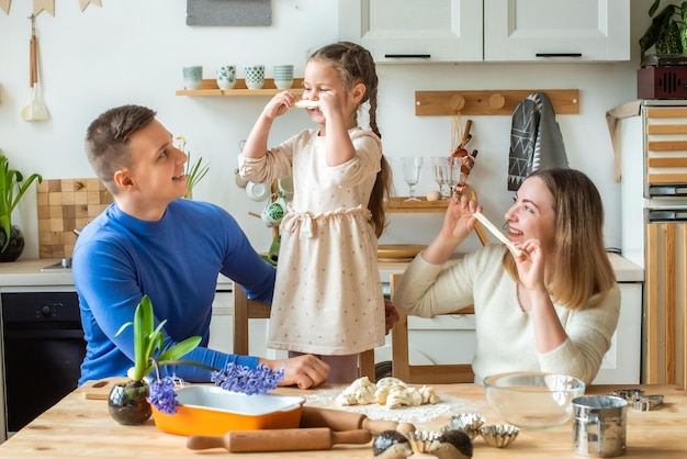 Cuochi di famiglia a casa mamma papà e figlia impastano insieme la pasta in una cucina uomo ragazza donna