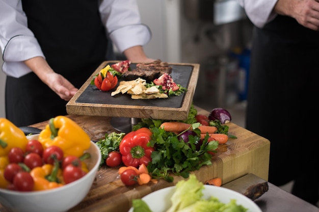 Cuochi e chef di squadra professionisti che preparano pasti nella cucina di un hotel o di un ristorante affollato