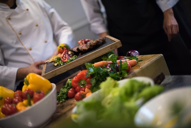 Cuochi e chef di squadra professionisti che preparano pasti nella cucina di un hotel o di un ristorante affollato