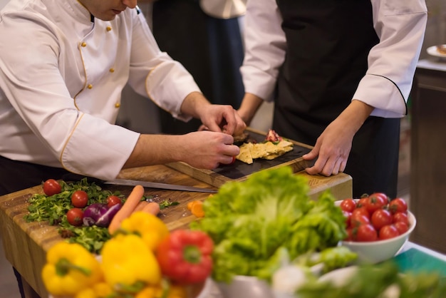 Cuochi e chef di squadra professionisti che preparano pasti nella cucina di un hotel o di un ristorante affollato