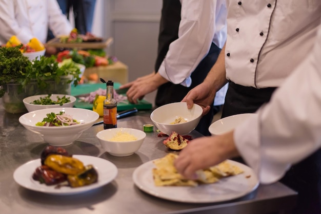 Cuochi e chef di squadra professionisti che preparano pasti nella cucina di un hotel o di un ristorante affollato