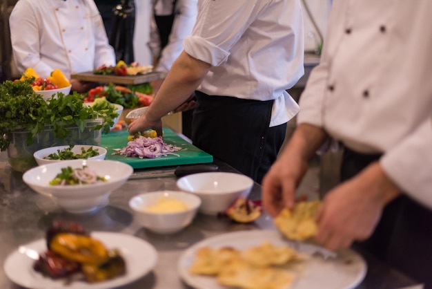 Cuochi e chef di squadra professionisti che preparano pasti nella cucina di un hotel o di un ristorante affollato