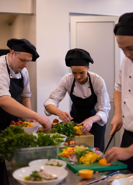 Cuochi e chef di squadra professionisti che preparano pasti nella cucina di un hotel o di un ristorante affollato