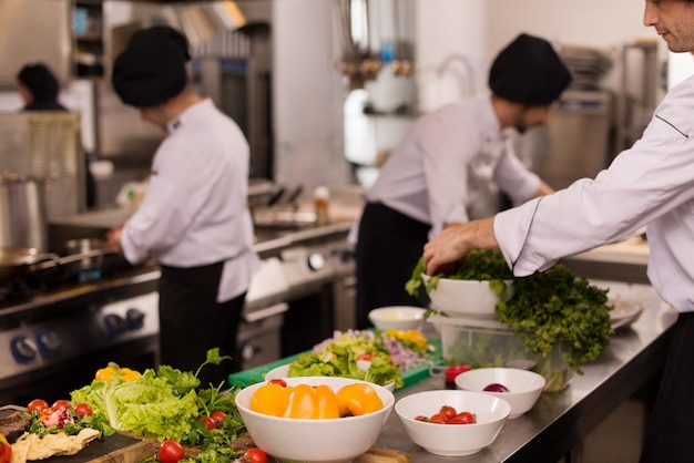 Cuochi e chef di squadra professionisti che preparano pasti nella cucina di un hotel o di un ristorante affollato