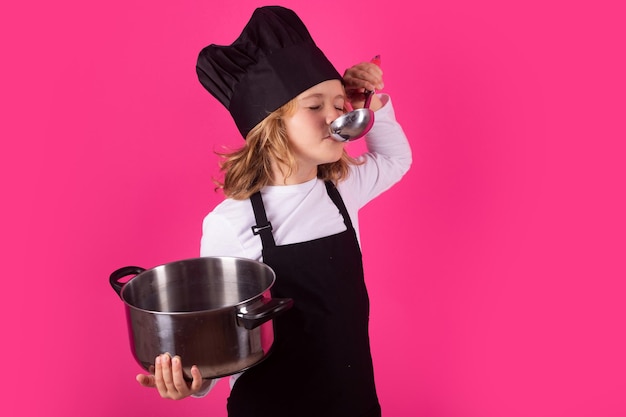 Cuoco bambino con pentola e mestolo Ritratto di bambino piccolo in uniforme di cuoco Ragazzo cuoco isolato su sfondo studio Bambino carino per essere uno chef Bambino vestito da cappello da cuoco