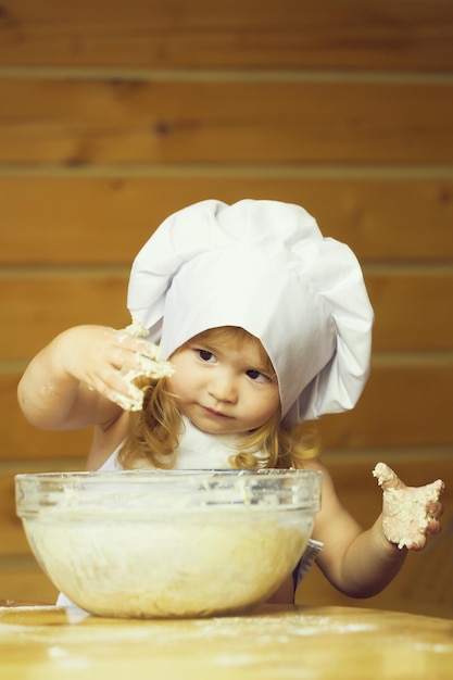 Cuoco bambino felice che impasta la pasta