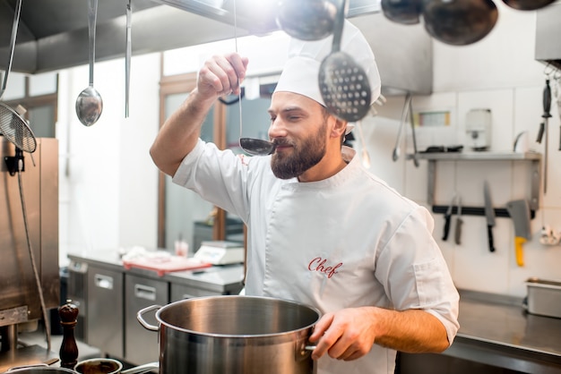 Cuoco chef che assaggia cibo con grande paletta nella cucina del ristorante?