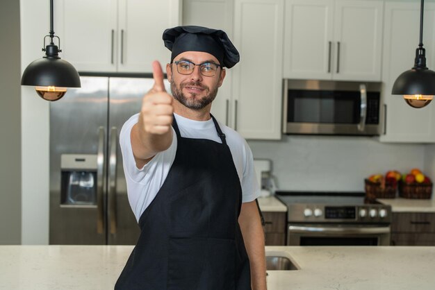 Cuoco cuoco felice con il pollice in su Ritratto di chef cuochi o fornaio Uomo con cappello da cuoco e uniforme da chef che cucina in cucina