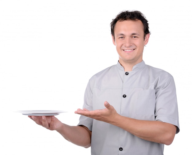 Cuoco del cuoco unico in uniforme che passa un piatto bianco.