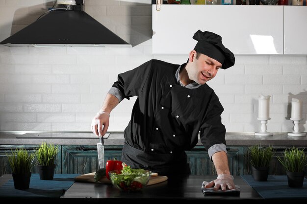 Cuoco dell'uomo che prepara il cibo al tavolo della cucina delle verdure