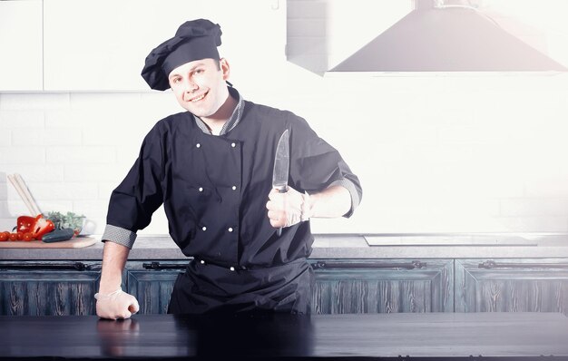 Cuoco dell'uomo che prepara il cibo al tavolo della cucina di verdure