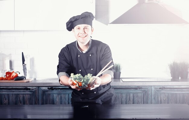 Cuoco dell'uomo che prepara il cibo al tavolo della cucina di verdure