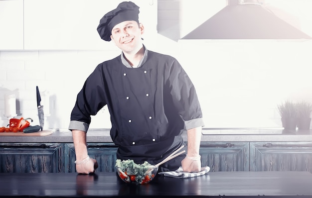 Cuoco dell'uomo che prepara il cibo al tavolo della cucina di verdure