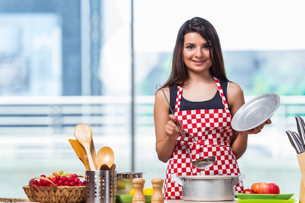 Cuoco femmina prepara la zuppa in cucina illuminata