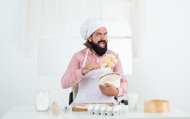 Cuoco maschio barbuto che prepara il cibo nella cucina domestica