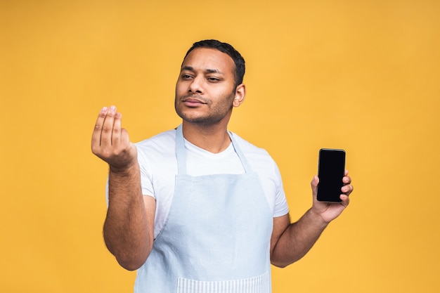 Cuoco o chef indiano afroamericano maschio nero che tocca il display del telefono cellulare, isolato su sfondo giallo, copia spazio, ritaglio.