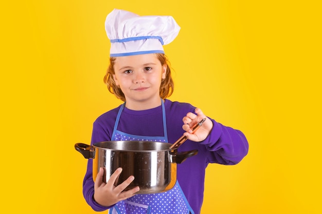 Cuoco per bambini con pentola e mestolo Bambino che indossa uniforme da cucina e cappello da chef che prepara il ritratto dello studio del cibo