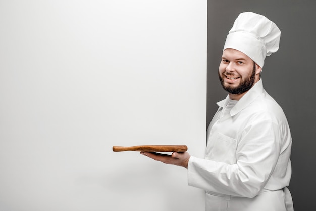 Cuoco sorridente con il tagliere vicino alla lavagna