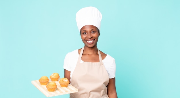 Cuoco unico adulto afroamericano nero che tiene in mano un vassoio di muffin