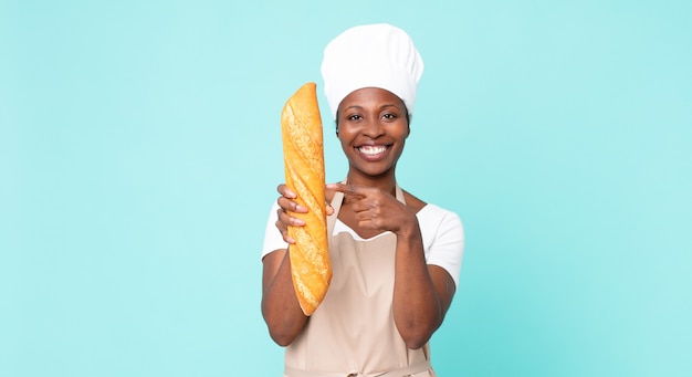 Cuoco unico adulto afroamericano nero che tiene una baguette di pane