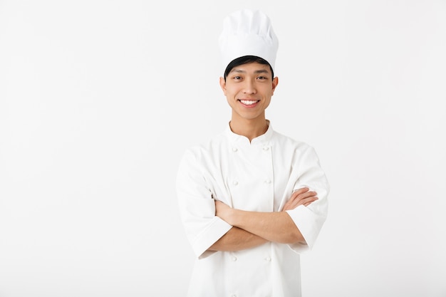 Cuoco unico asiatico emozionante che indossa la condizione uniforme isolata sopra la parete bianca, gesticolando