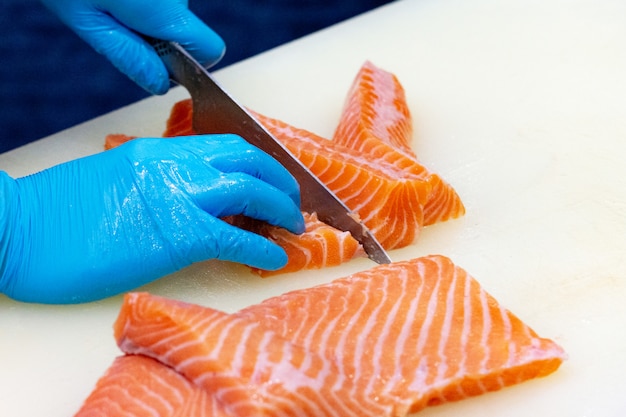 Cuoco unico che affetta il salmone fresco crudo, cuoco unico che prepara un salmone fresco su un tagliere